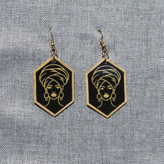 Black and gold hexagon earring. Black background with gold trim. Gold outlined woman with head wrap applique.