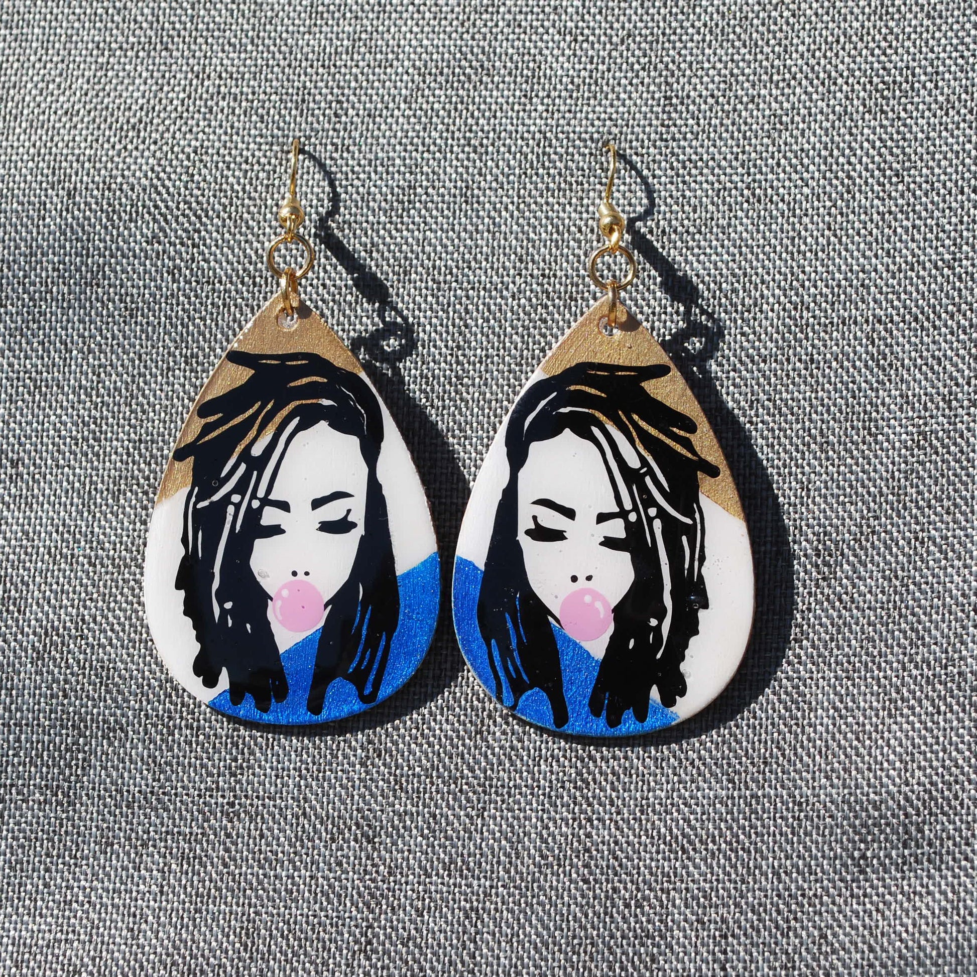 Gold, white, and blue teardrop shaped earring.  Length 2". Loc'd woman with bubble gum applique.