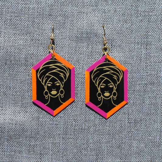 Black, pink, orange, and gold hexagon earring. Black background with pink and orange trim. Gold outlined woman with head wrap applique.